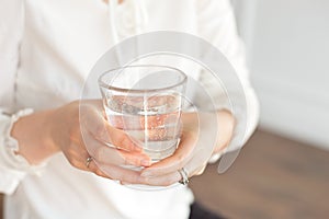 Glass of clean mineral water in woman`s hands. Concept of environment protection, healthy drink