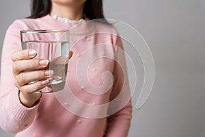 A glass of clean mineral water in woman`s hands. Concept of environment protection, healthy drink and healthcare