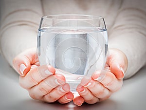 A glass of clean mineral water in woman's hands. Environment protection, healthy drink.