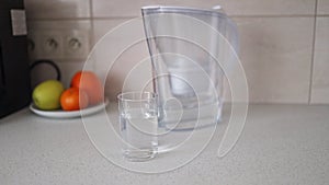 A glass of clean water with a filter jar on a table in kitchen interior. Concept of a water treatment.