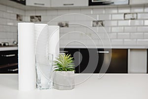 A glass of clean water with osmosis filter and cartridges on white table in a kitchen interior. Concept Household filtration