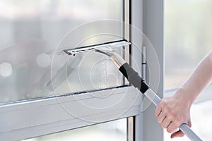 Glass cleaner using a squeegee to wash a window.