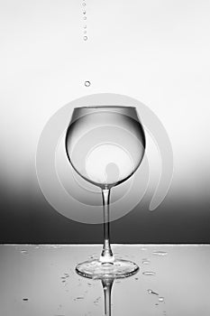 A glass of clear liquid and a drop falling into it