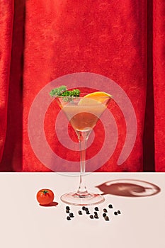 A glass of cocktail bloody Mary with some tomato and pepper on the bottom in front of red velvet curtain. Theatre modern celebrity