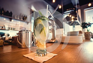 Glass of cocktail with lemon and mint on table