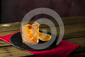Glass of the cocktail negroni on a old wooden board. Drink with gin, campari martini rosso and orange, an italian cocktail, an