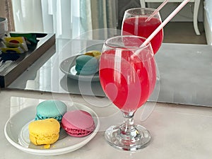 Glass with cocktail and plate with colourful macarons
