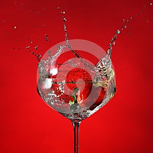 Glass with cocktail and splashing strawberry