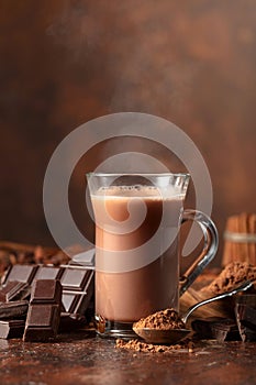 Glass of cocoa drink with ingredients on a brown table