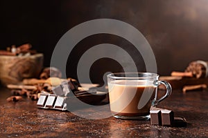 Glass of cocoa drink and pieces of dark chocolate on a brown vintage table