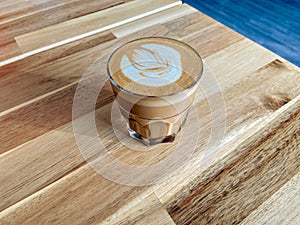 A glass of coffee latte on wooden texture of the table