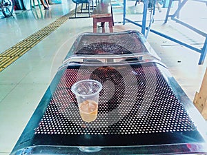 a glass of coffee with milk during the day on a long metal bench