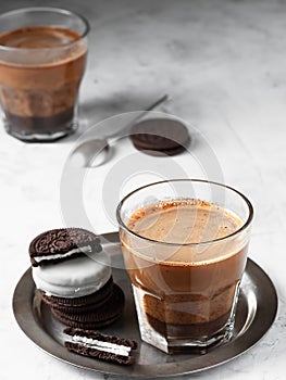 Glass of coffee with milk on a metal dish with chocolate chip cookies. Coffee is located on a light gray background. Top view,