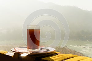 glass of coffee with mountain and river at morning sunrise. Foggy frosty morning in the mountains of the Himalayas. Ganges river.