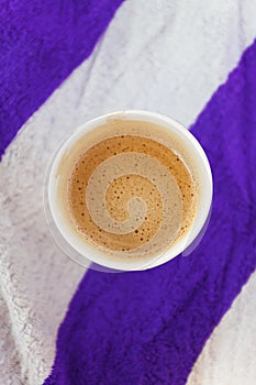 Glass with coffee on a striped beach towel. Abstract colors. Top view, copy space, flat lay