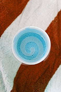 Glass with coffee on a striped beach towel. Abstract colors. Top view, copy space, flat lay