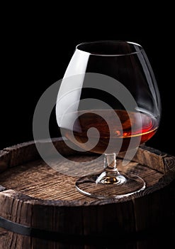 Glass of cognac brandy drink on top of wooden barrel.