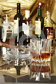 Glass of cognac, brandy or whiscy on mirror table. bottles in a bar on the background