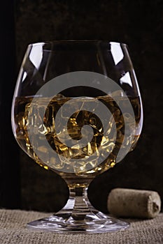 Glass of cognac with ice closeup background