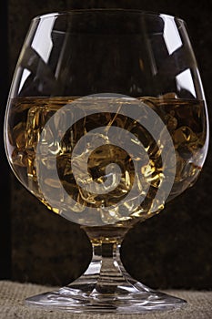 Glass of cognac with ice closeup background