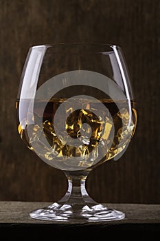 Glass of cognac with ice closeup on cloth background