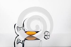 Glass with cognac or whiskey on a white background and a cube of ice