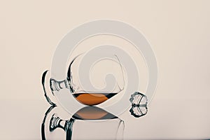 Glass with cognac or whiskey on a white background and a cube of ice