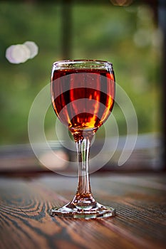 Glass of cognac on wooden table. Shot glass.