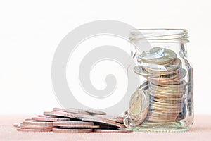 Glass of coin and spread coin on floor on vintage blurred background - Saving money concept.