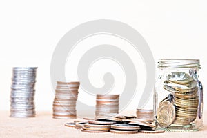 Glass of coin and spread coin on floor on vintage blurred background - Saving money concept.