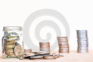 Glass of coin and spread coin on floor on vintage blurred background - Saving money concept.