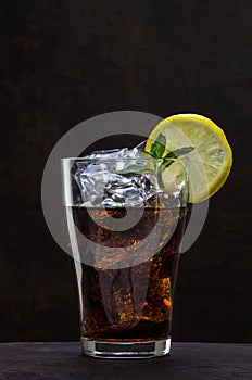 Glass of cola or coke with ice cubes, lemon slice and peppermint