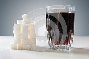 Glass of cola drink and heap of sugar cubec. Unhealthy eating concept