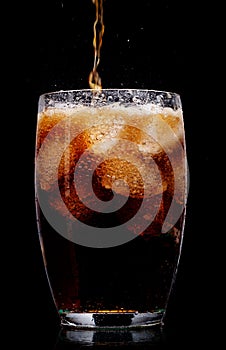 Glass of cola with ice on black background.