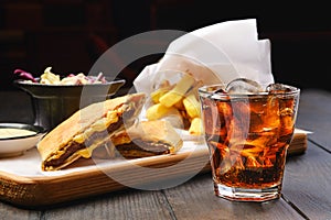 Glass of cola with ice with tortilla and fried potato on background