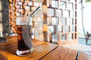 Glass of cola with ice on wood table on a hot day os Summer