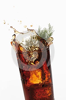 Glass of Cola and Southernwood splashing, close-up photo