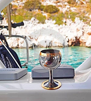 A glass with a cold alcoholic drink on the deck of a yacht during a summer sea vacation on a sunny day against a blurred