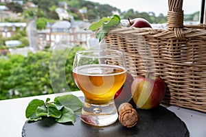 Glass of cold apple cider drink and houses of Etretat village on background, Normandy, France