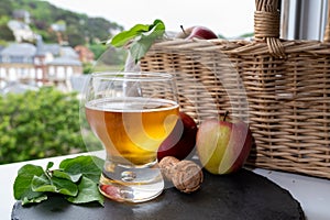 Glass of cold apple cider drink and houses of Etretat village on background, Normandy, France