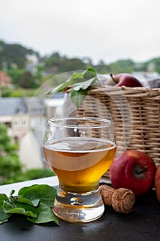 Glass of cold apple cider drink and houses of Etretat village on background, Normandy, France