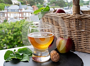 Glass of cold apple cider drink and houses of Etretat village on background, Normandy, France