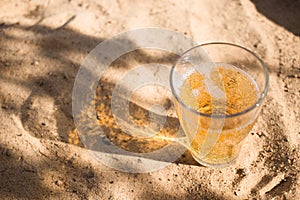 a glass of Cold beer on the beach, the shadow of the glass on the sand