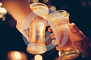 Glass of cold beer bottoms up with beautiful bokeh, friends drink beer together