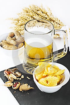 Glass of cold beer with chips and peanuts isolated on white back