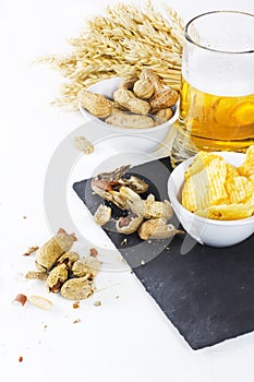 Glass of cold beer with chips and peanuts isolated on white back