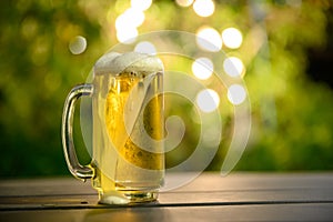 A glass of cold beer with a foam on top Placed on a table in the garden