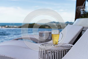 Glass of cold beer by swimming pool with blur sea view photo