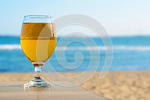 Glass of cold beer on wooden table at beach. Space for text