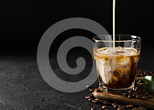 glass cold brew coffee with ice and milk on black or dark background